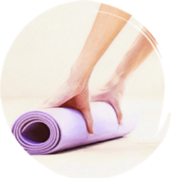 A woman rolling a purple yoga mat